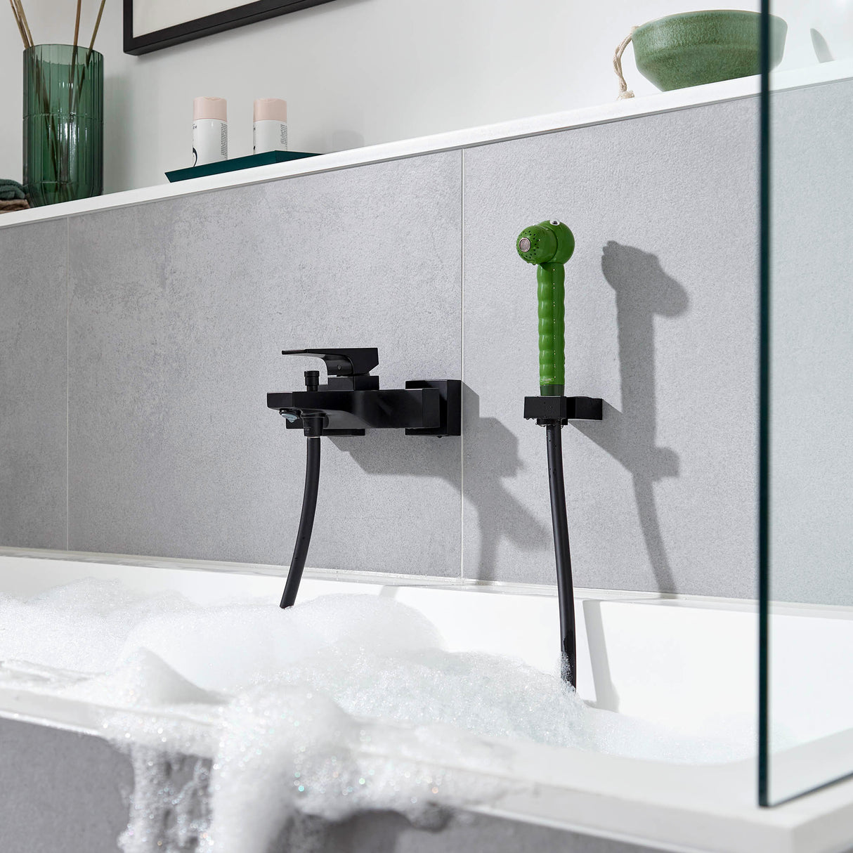 Mitigeur bain-douche noir Hansgrohe avec douchette verte, installé sur baignoire blanche.