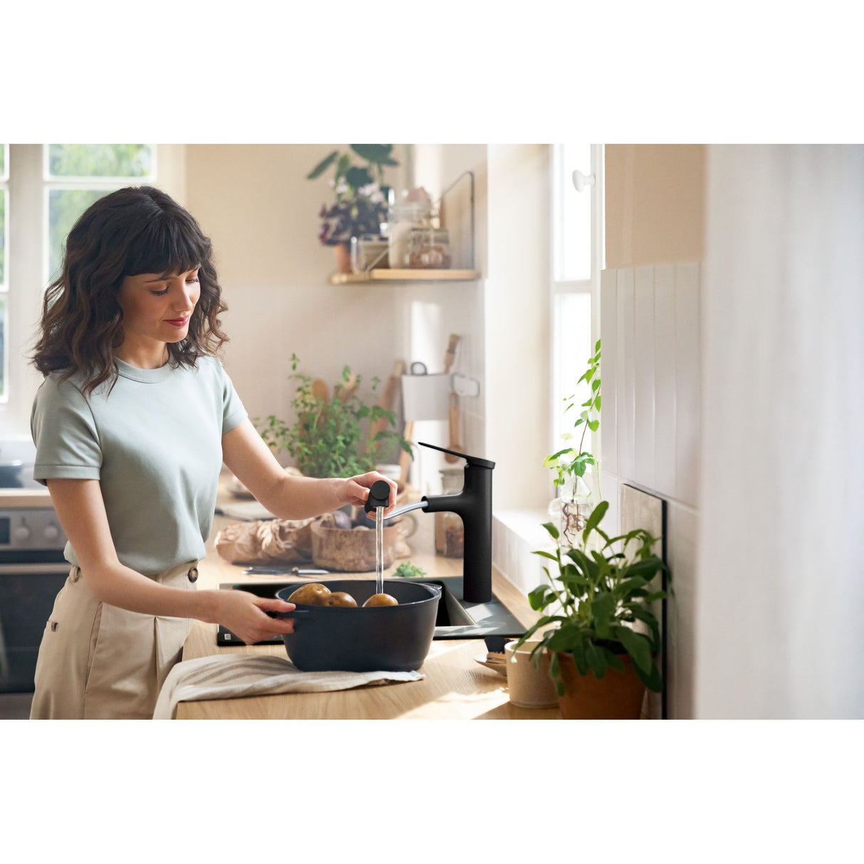 Robinet Grohe noir, mitigeur de cuisine design, femme remplissant une casserole d'eau.