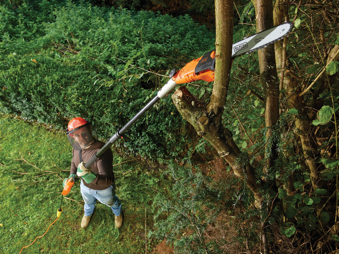 Élagueuse télescopique Black+Decker orange utilisée pour couper des branches d'arbre.