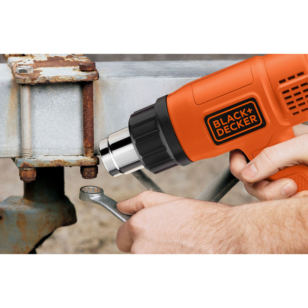 Décapeur thermique Black & Decker orange utilisé sur boulon rouillé, outillage électrique.