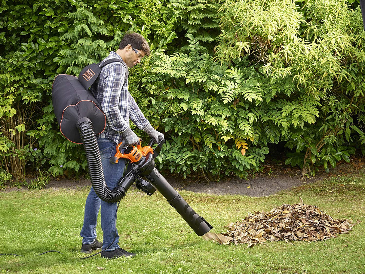 Homme utilisant un souffleur aspirateur Black+Decker orange et noir pour feuilles mortes dans un jardin