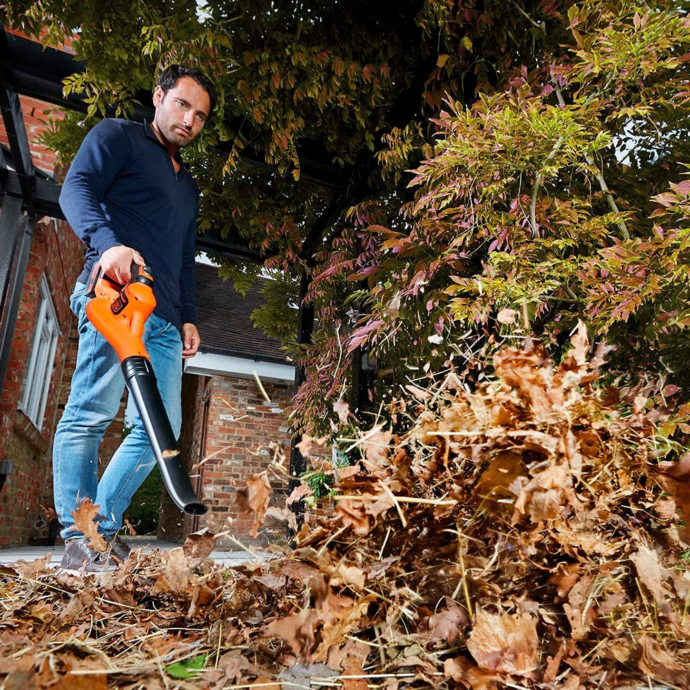 Souffleur de feuilles Black+Decker orange utilisé pour nettoyer des feuilles mortes, outil de jardin.
