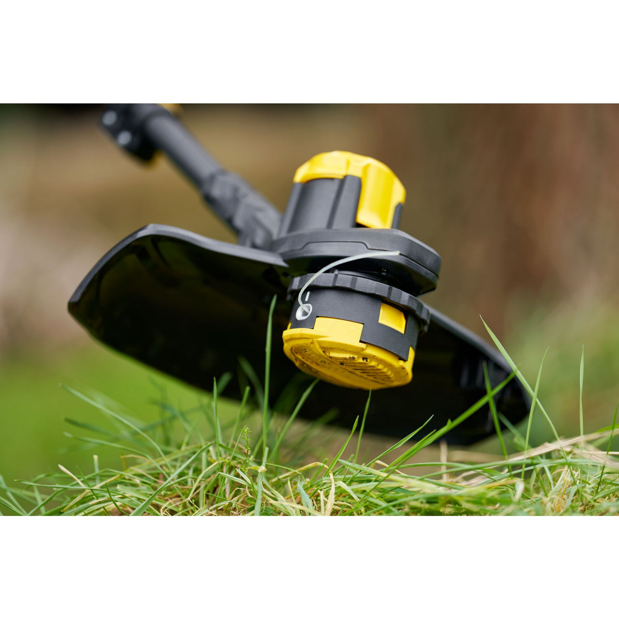 Tête de coupe de débroussailleuse DeWalt, jaune et noire, sur herbe verte