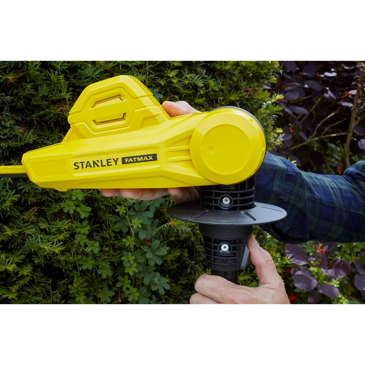 Taille-haie Stanley Fatmax jaune en action dans un jardin