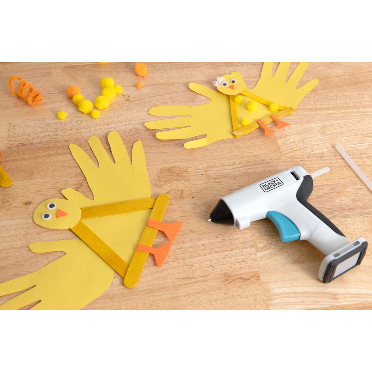 Pistolet à colle Black+Decker, outil électrique blanc et noir, posé sur table en bois.