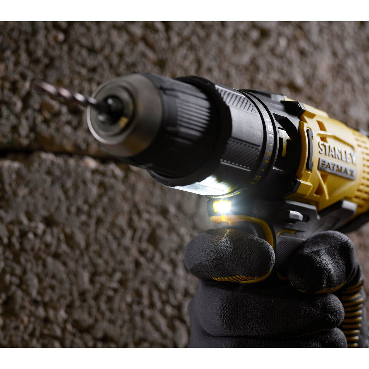 Perceuse visseuse Stanley FATMAX noire et jaune en action contre un mur, outil électroportatif