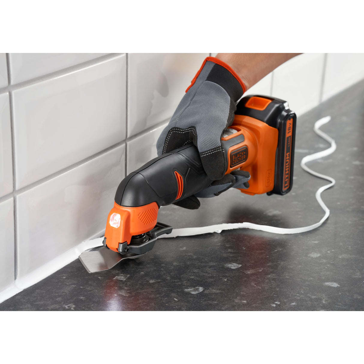 Outil multifonction Black+Decker, coupeur électrique orange et noir, utilisé pour enlever du joint.
