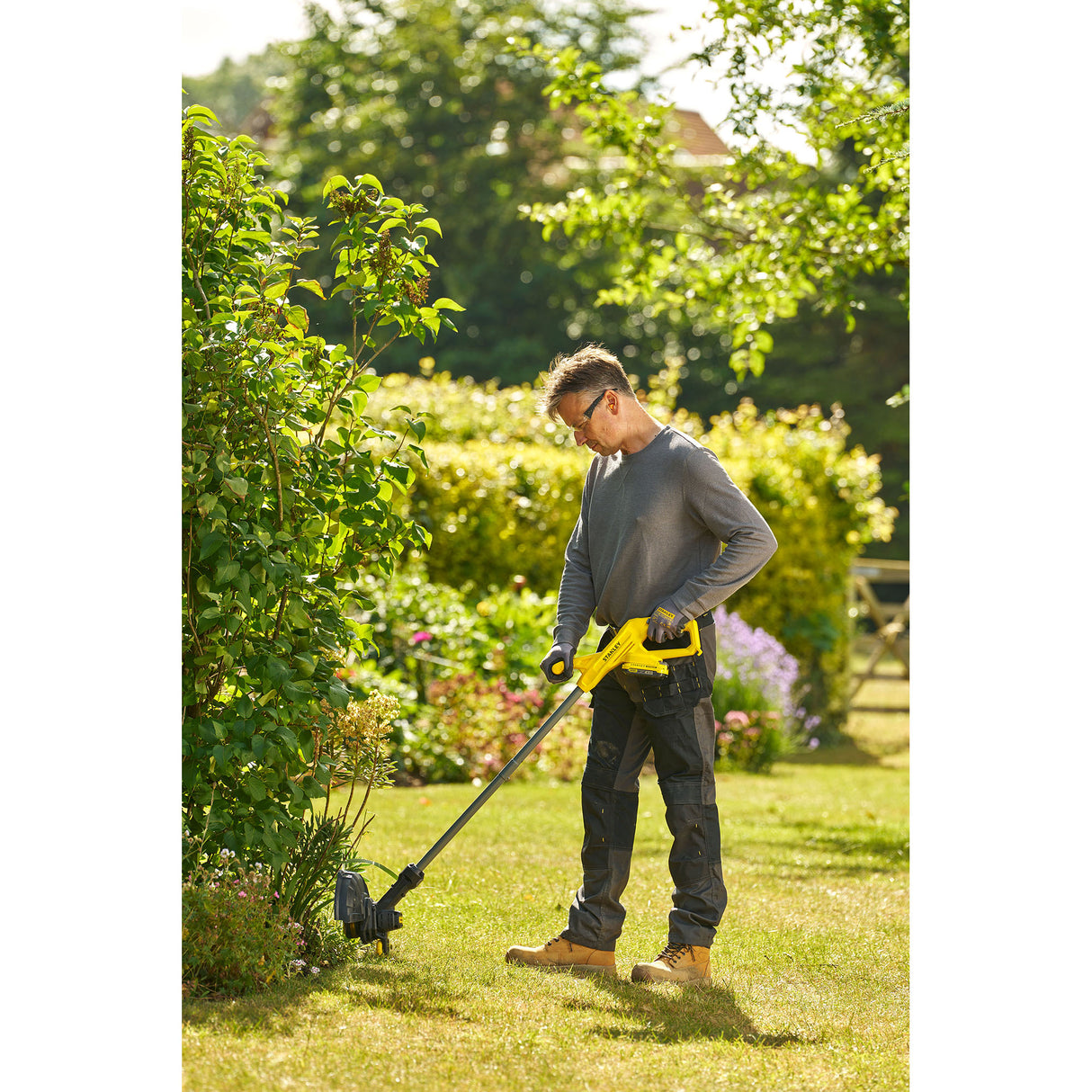 Homme utilisant un coupe-bordures jaune Karcher, outil de jardin, couleur jaune, extérieur