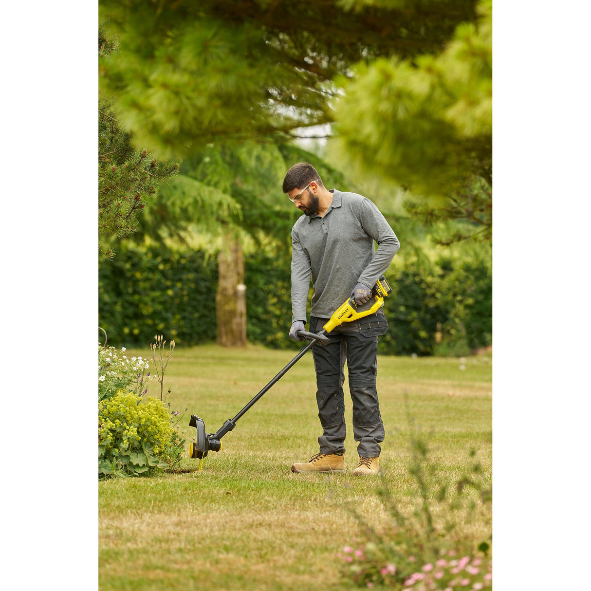 Coupe-bordure jaune Dewalt utilisé en extérieur, outil de jardinage électroportatif.