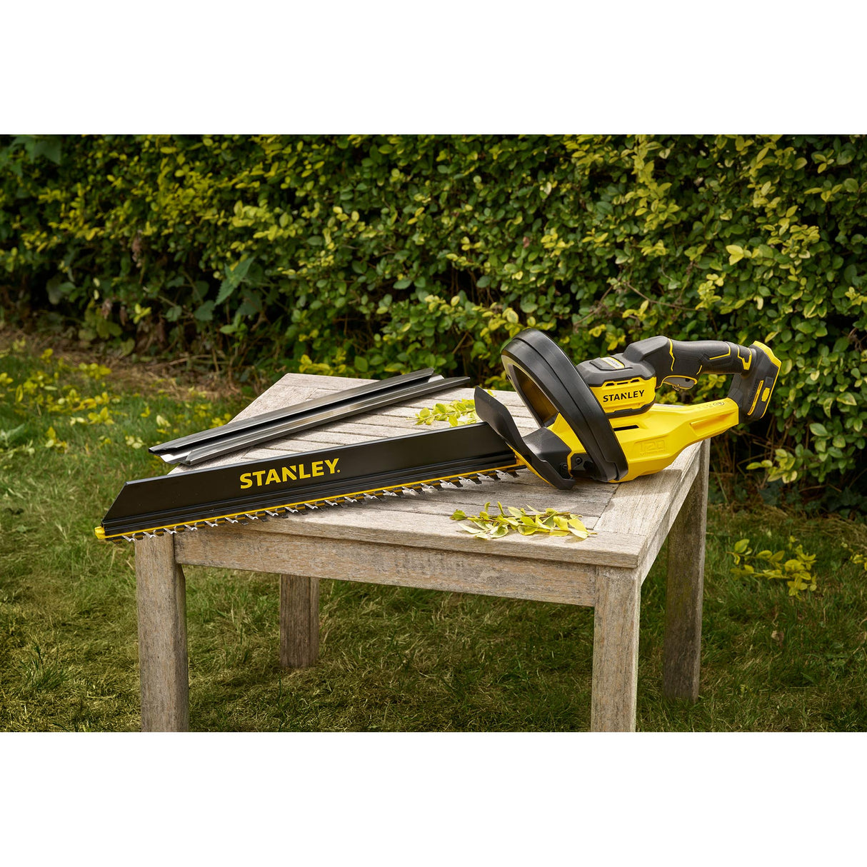 Taille-haie Stanley électrique jaune et noir posé sur une table en bois, outil de jardinage