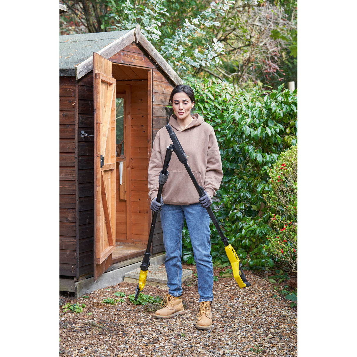 Femme tenant un désherbeur électrique Kärcher jaune pour jardin, outil de jardinage.