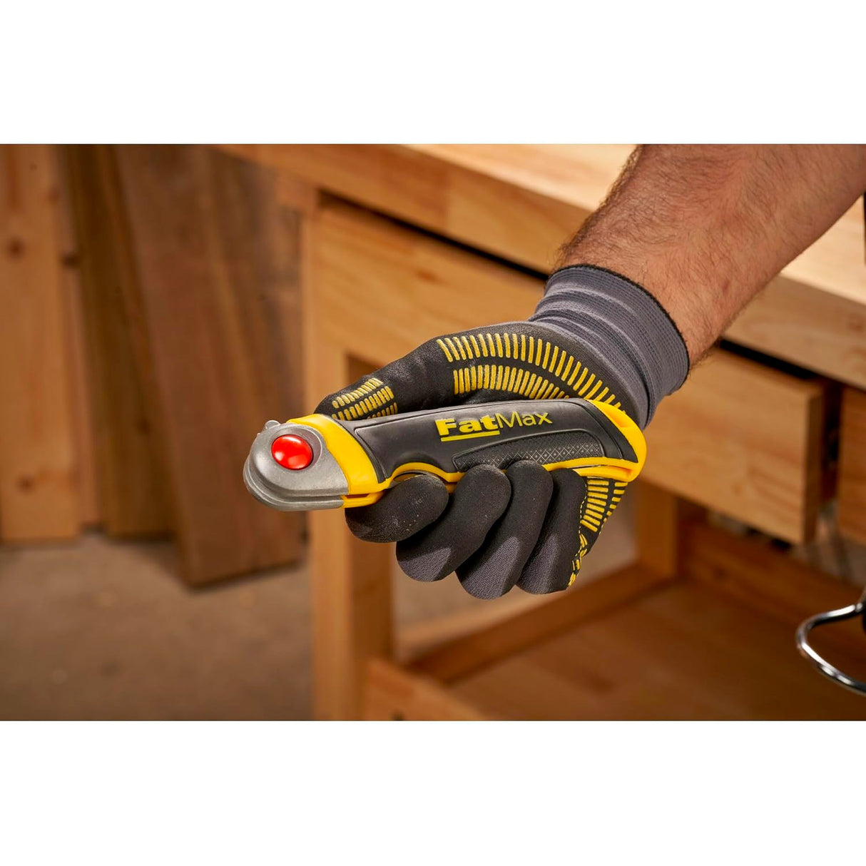 Cutter Stanley FatMax, outil de coupe, couleur jaune et noir, en main dans un atelier