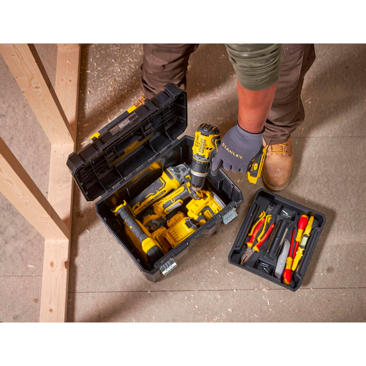 Perceuse sans fil jaune marque Stanley, type outillage, dans une boîte à outils noire.