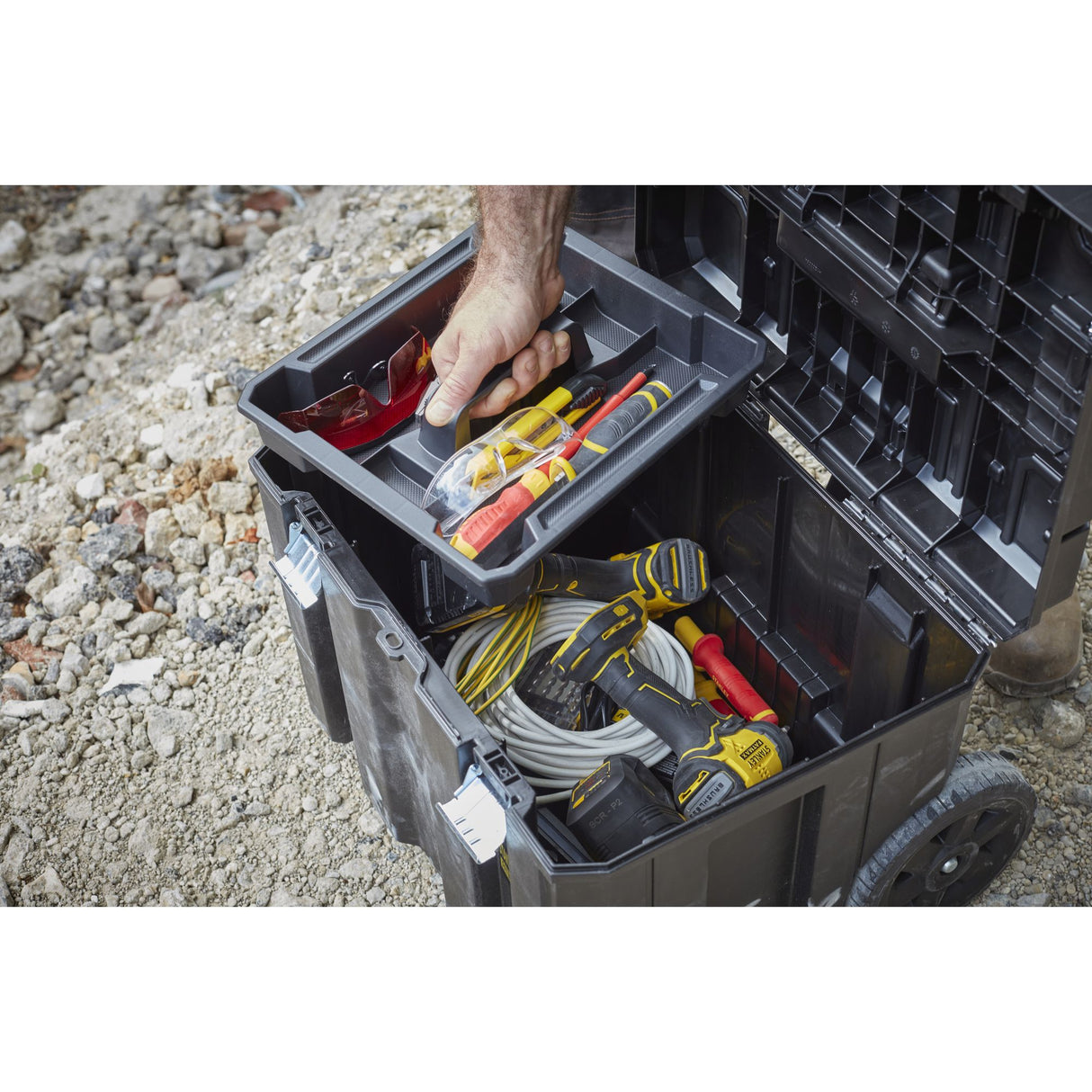 Caisse à outils Stanley noire, outils jaunes et gris, sur chantier
