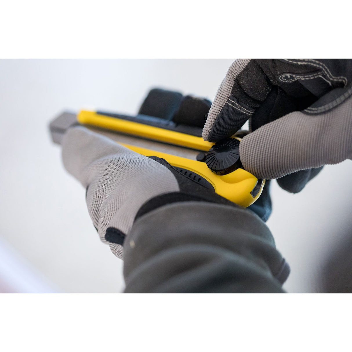 Cutter Stanley jaune, outil de coupe, lame réglable, tenue en main avec gants de travail