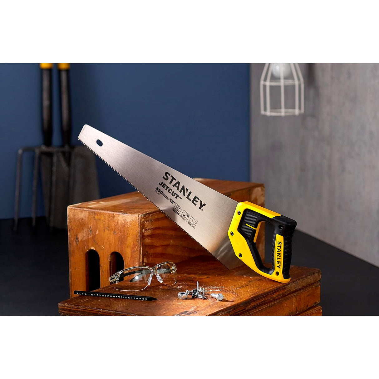 Scie à main Stanley JetCut, poignée noire et jaune, posée sur une caisse en bois.