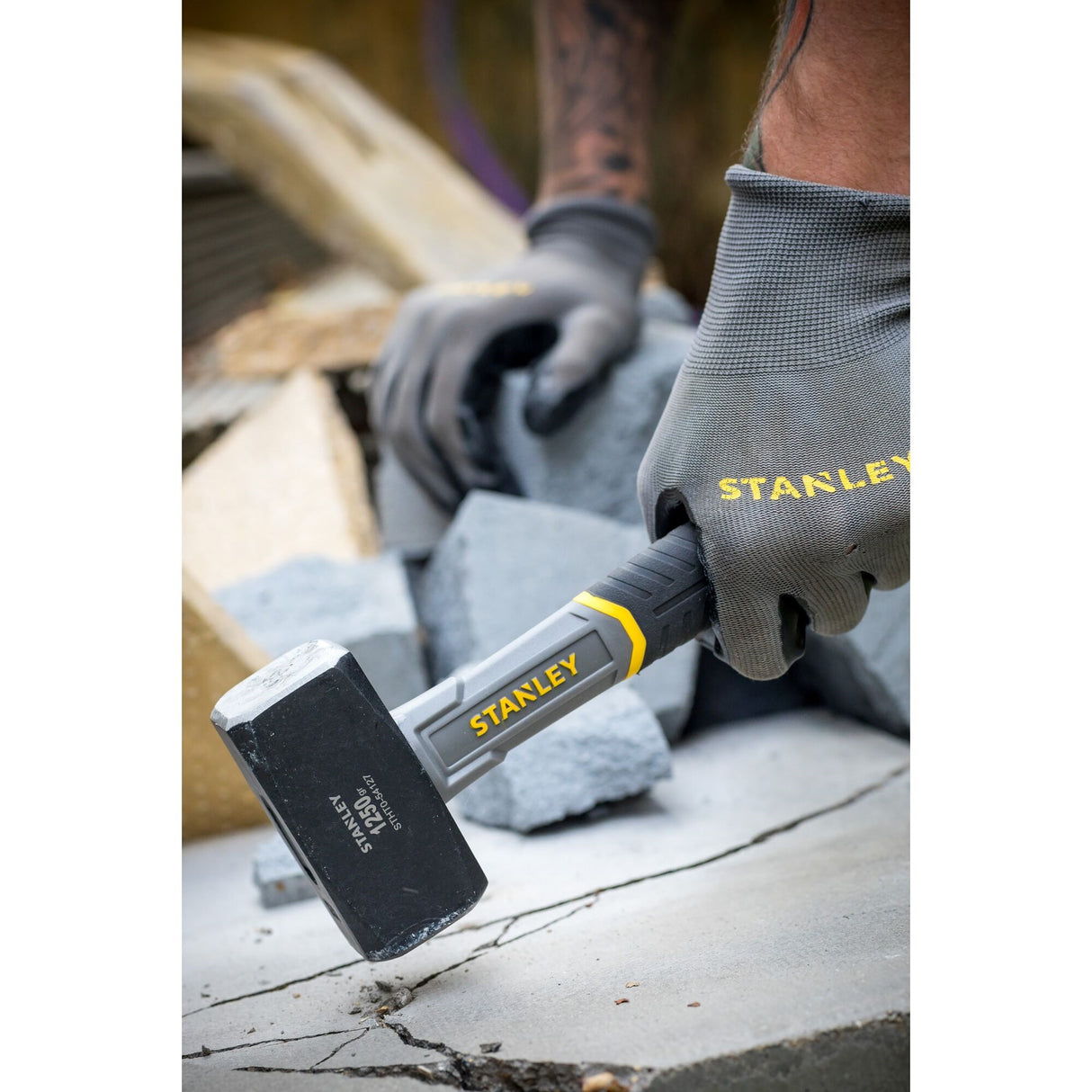 Marteau Stanley gris et jaune en action pour travaux de maçonnerie, outil à main