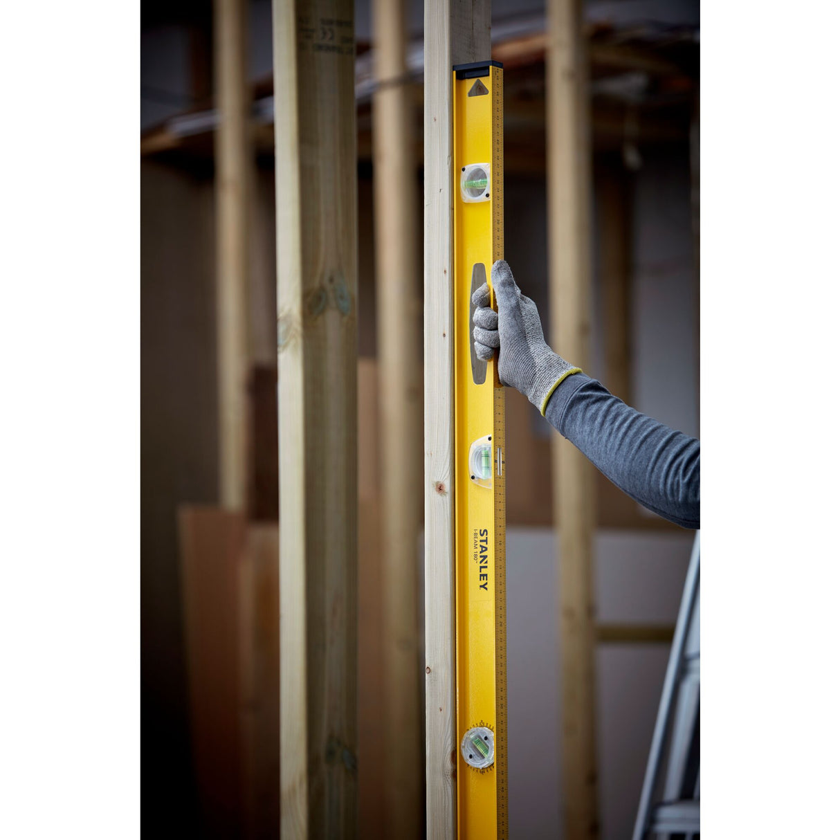 Niveau à bulle Stanley jaune, outil de mesure, utilisé sur un montant en bois.