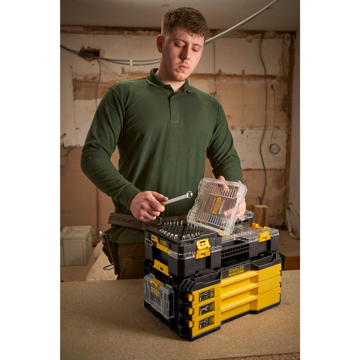 Homme utilisant une boîte à outils Stanley, couleur jaune et noir, type coffret à outils.