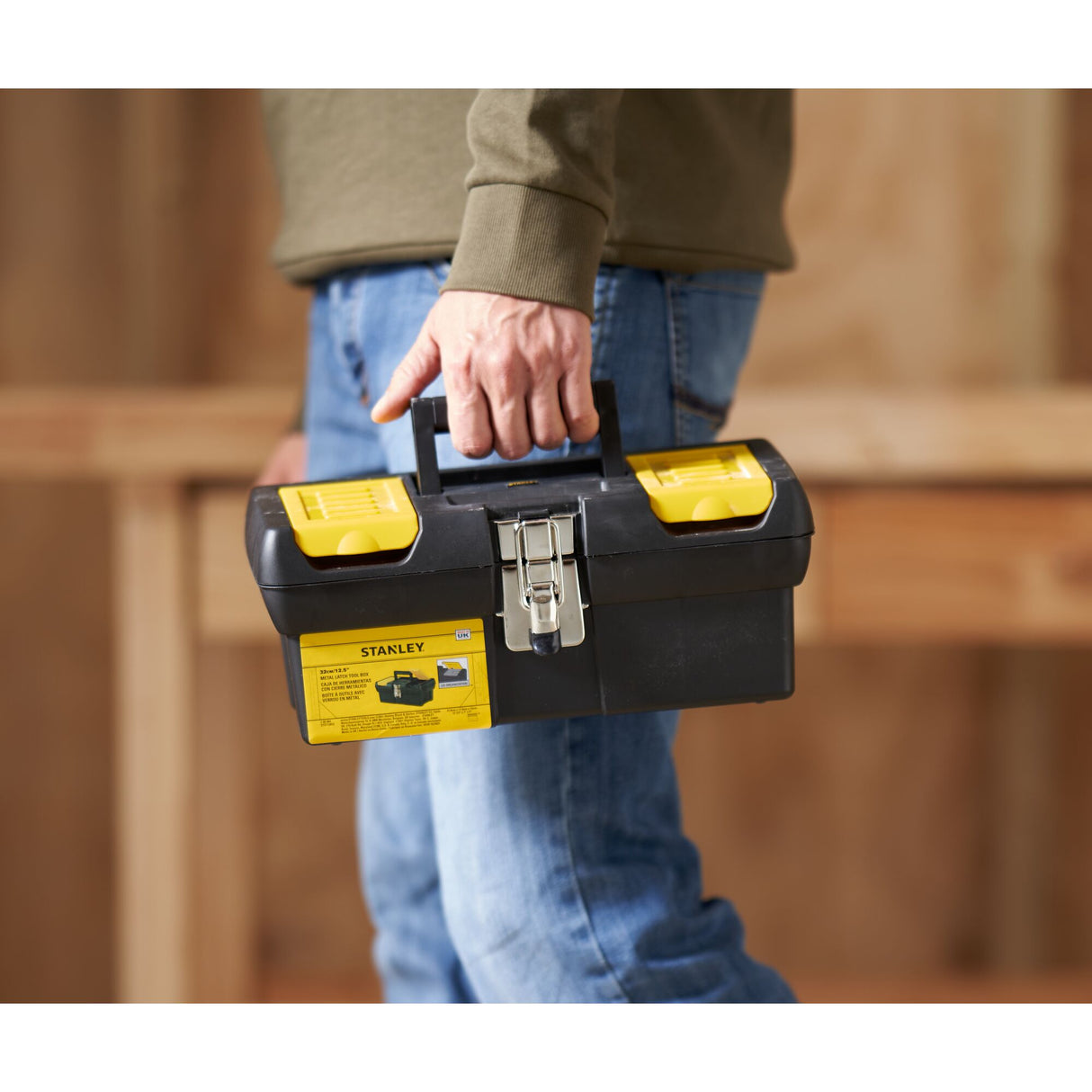 Boîte à outils Stanley noire et jaune, portée à la main, idéale pour bricolage.