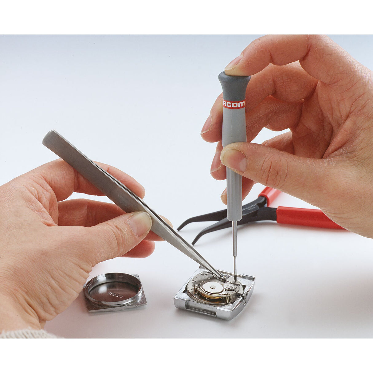 Tournevis de précision Facom gris utilisé pour réparer une montre, outillage gris et rouge.