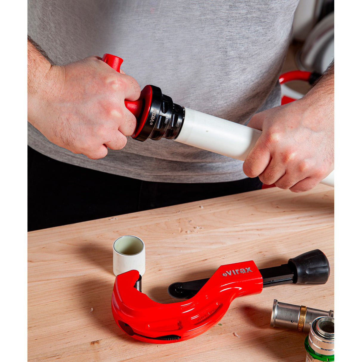 Coupure de tube blanc avec coupe-tube Virax rouge, outil de plomberie professionnel.