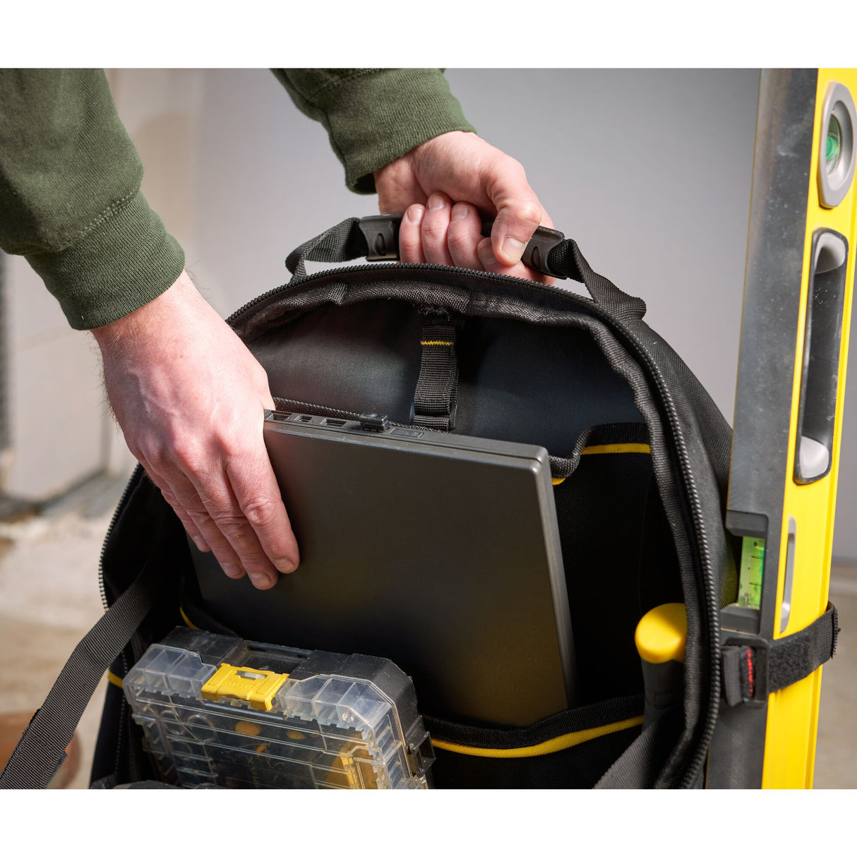 Sac à outils noir Stanley avec niveau à bulle jaune, boîte à outils et ordinateur portable.