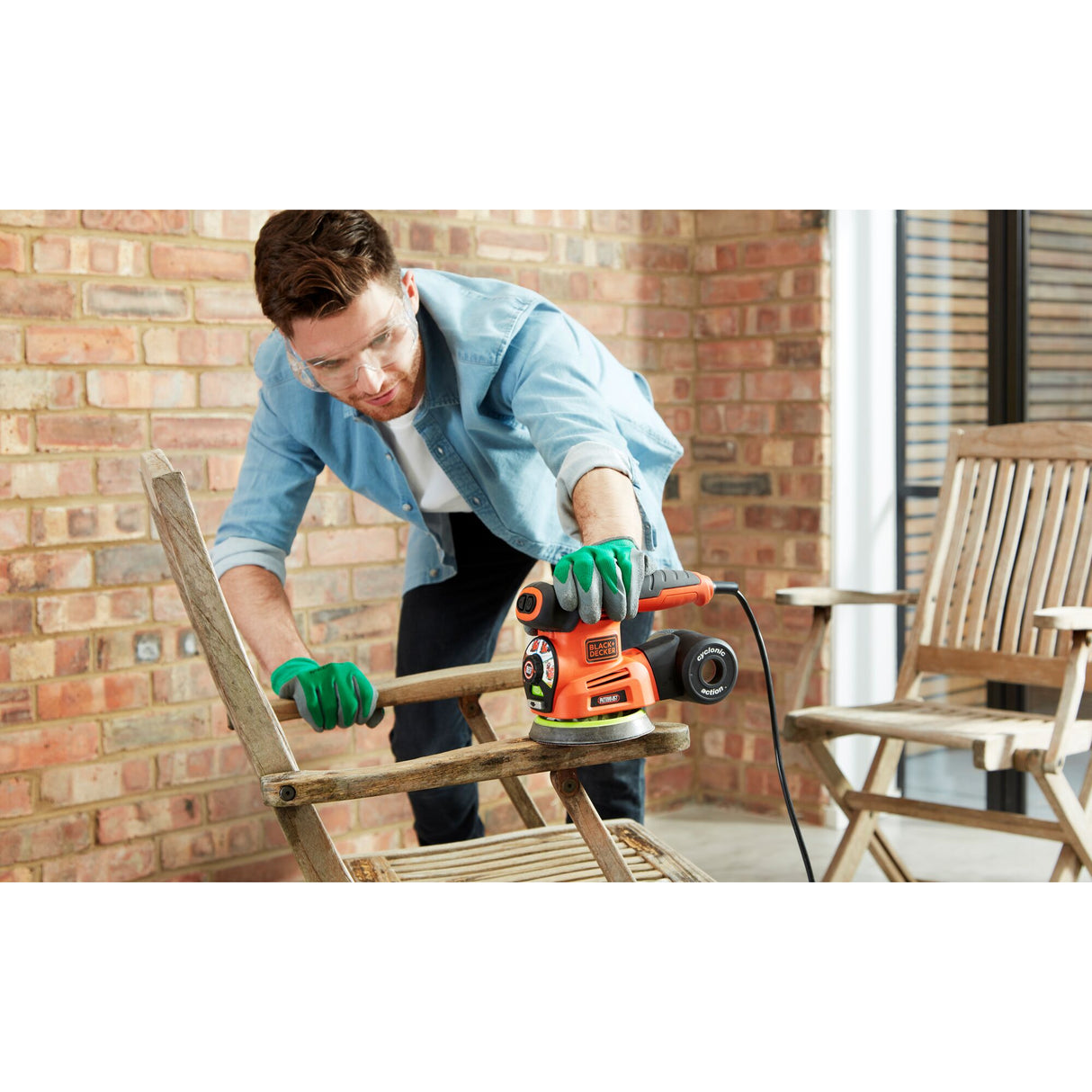 Homme utilisant une ponceuse orange Black+Decker, ponçage bois, outil électrique, couleur orange