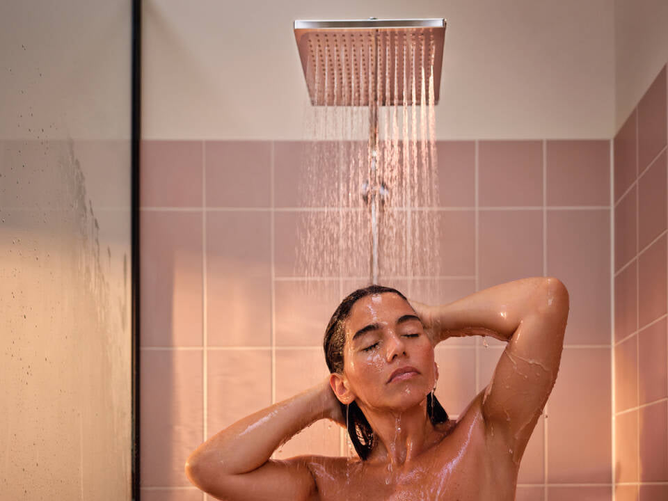 Douchette pluie Crometta Showerpipe Hansgrohe chromée, femme sous la douche moderne rose.