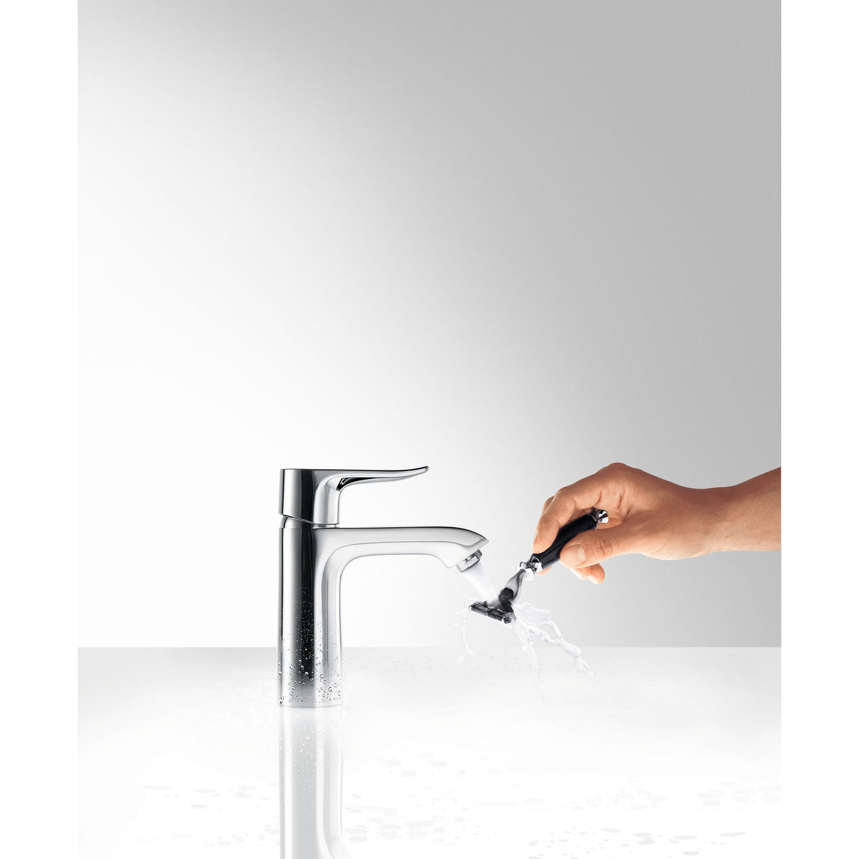 Robinet lavabo chromé Hansgrohe, mitigeur design, couleur argent, main rinçant un rasoir