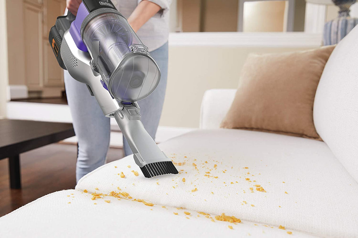 Aspirateur à main BLACK+DECKER, type sans fil, couleur gris et violet, nettoyant un canapé blanc