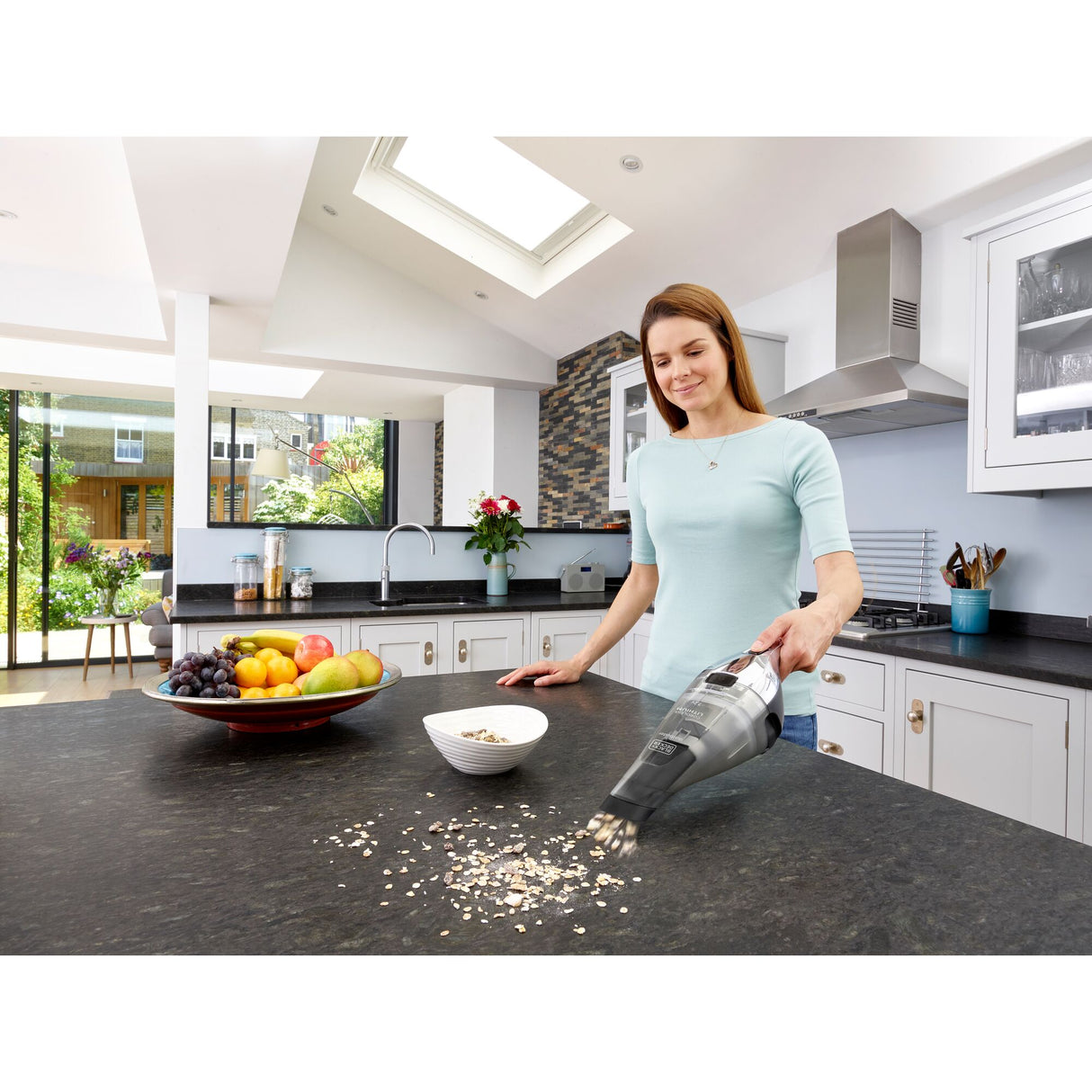 Aspirateur à main Black+Decker, noir, utilisé dans une cuisine moderne pour nettoyer un plan de travail.