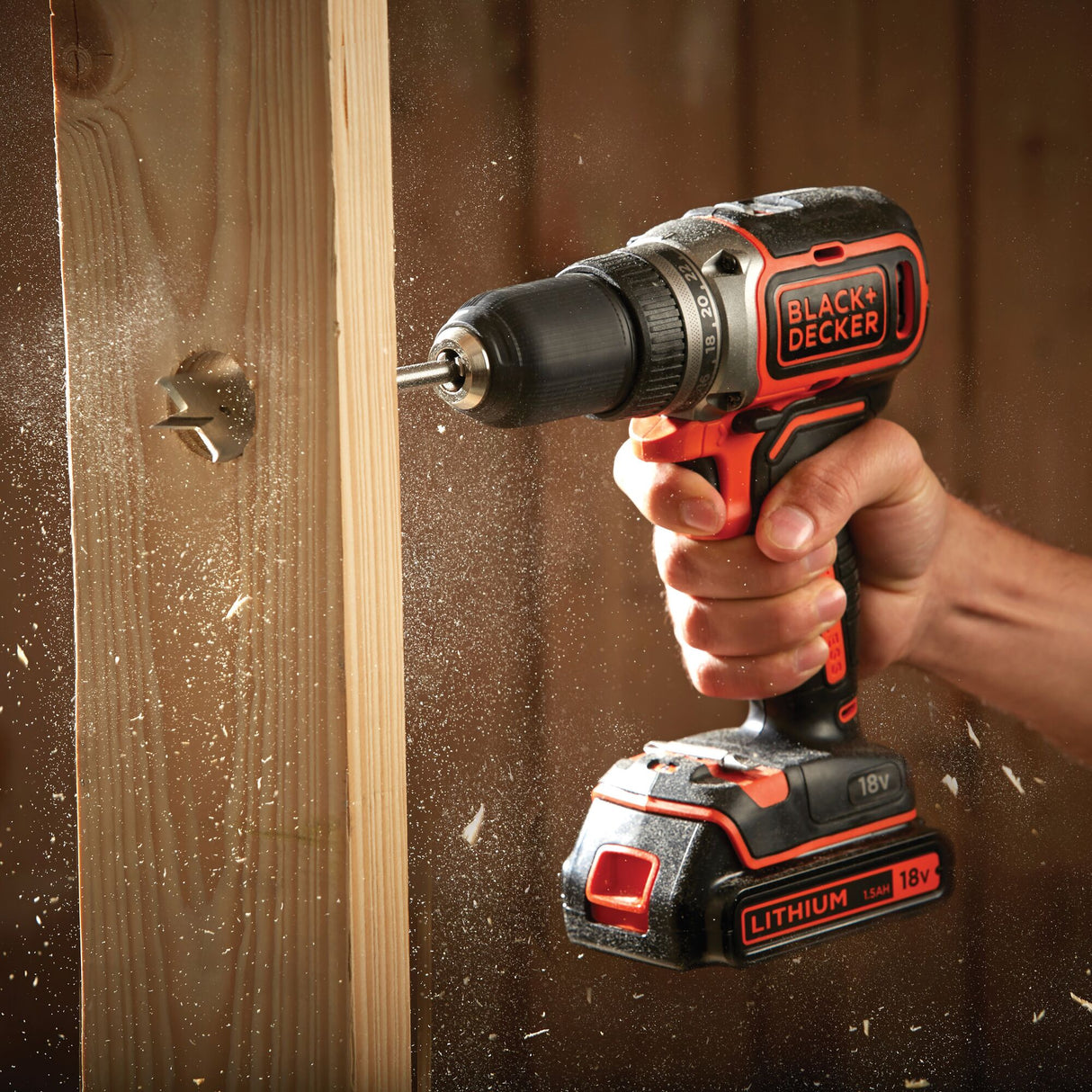 Perceuse visseuse Black+Decker sans fil, couleur noire et orange, en action sur bois