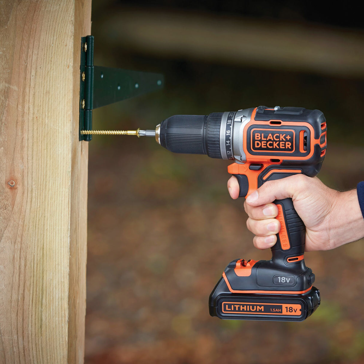 Perceuse sans fil BLACK+DECKER, couleur noire et orange, utilisée pour visser dans du bois.