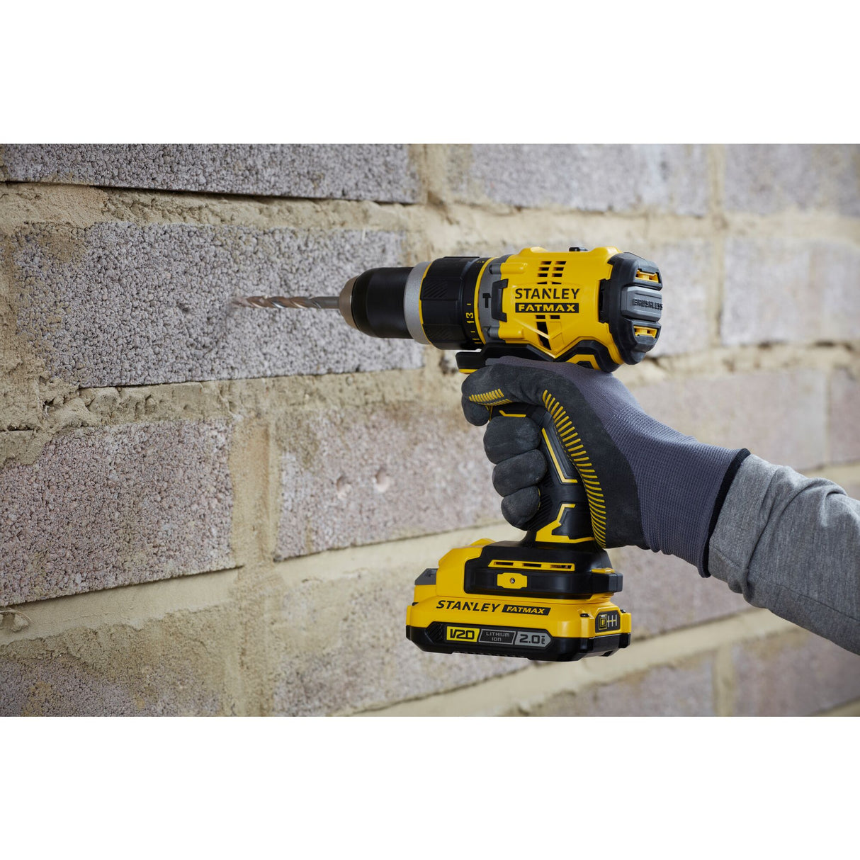 Perceuse-visseuse sans fil jaune Stanley Fatmax utilisée sur un mur, outil électroportatif.