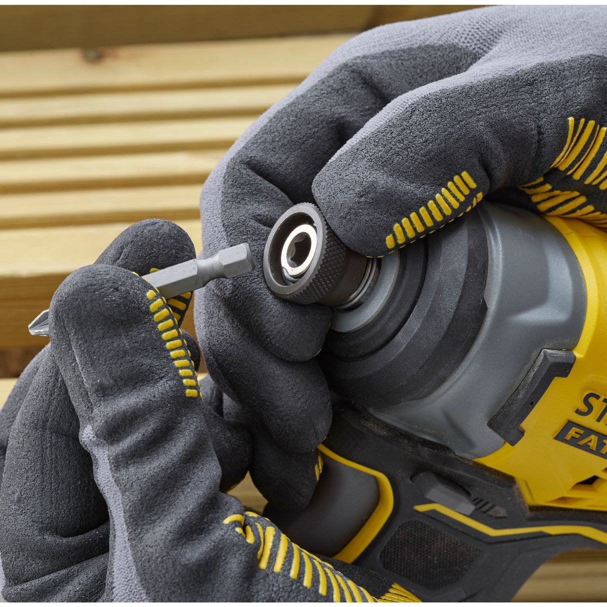 Perceuse-visseuse jaune Stanley, outil électroportatif, tenue par des gants gris.