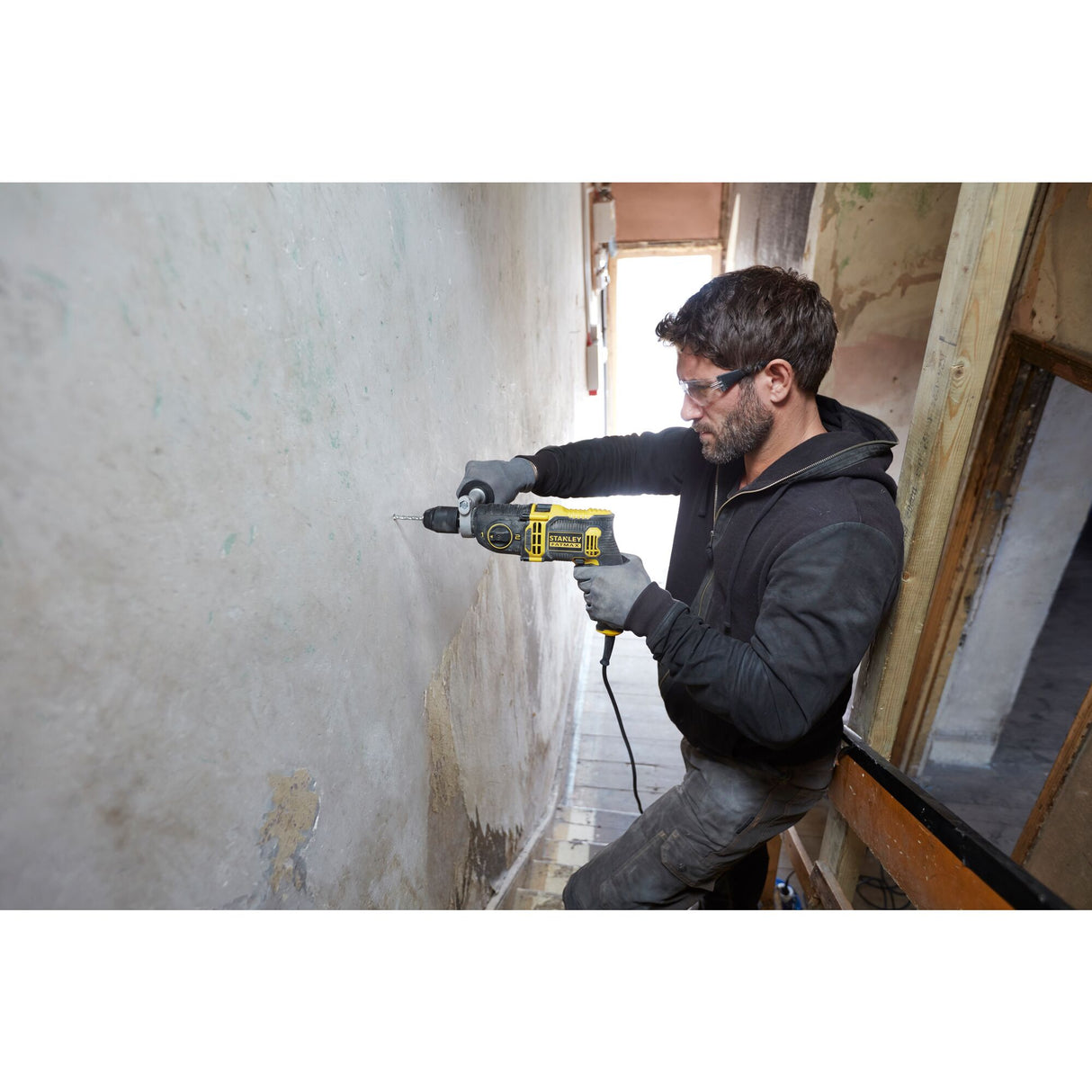 Perceuse jaune Stanley, outil électroportatif, utilisée sur un mur, couleur noire et jaune.