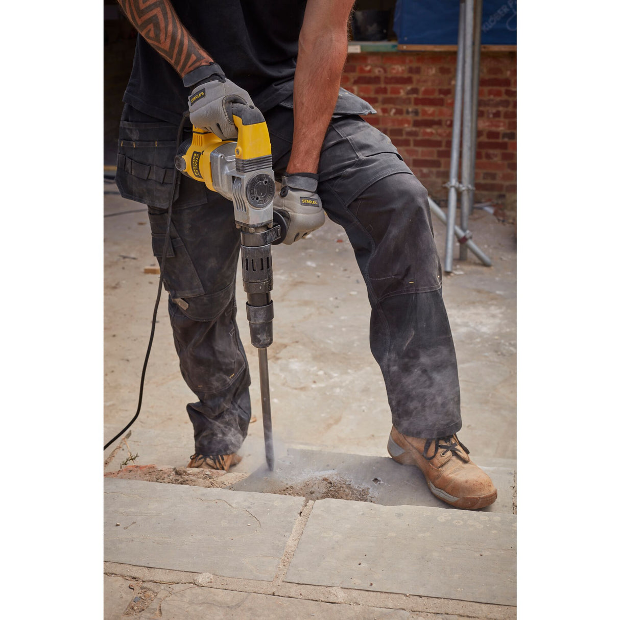 Marteau perforateur Stanley jaune et gris en action sur chantier