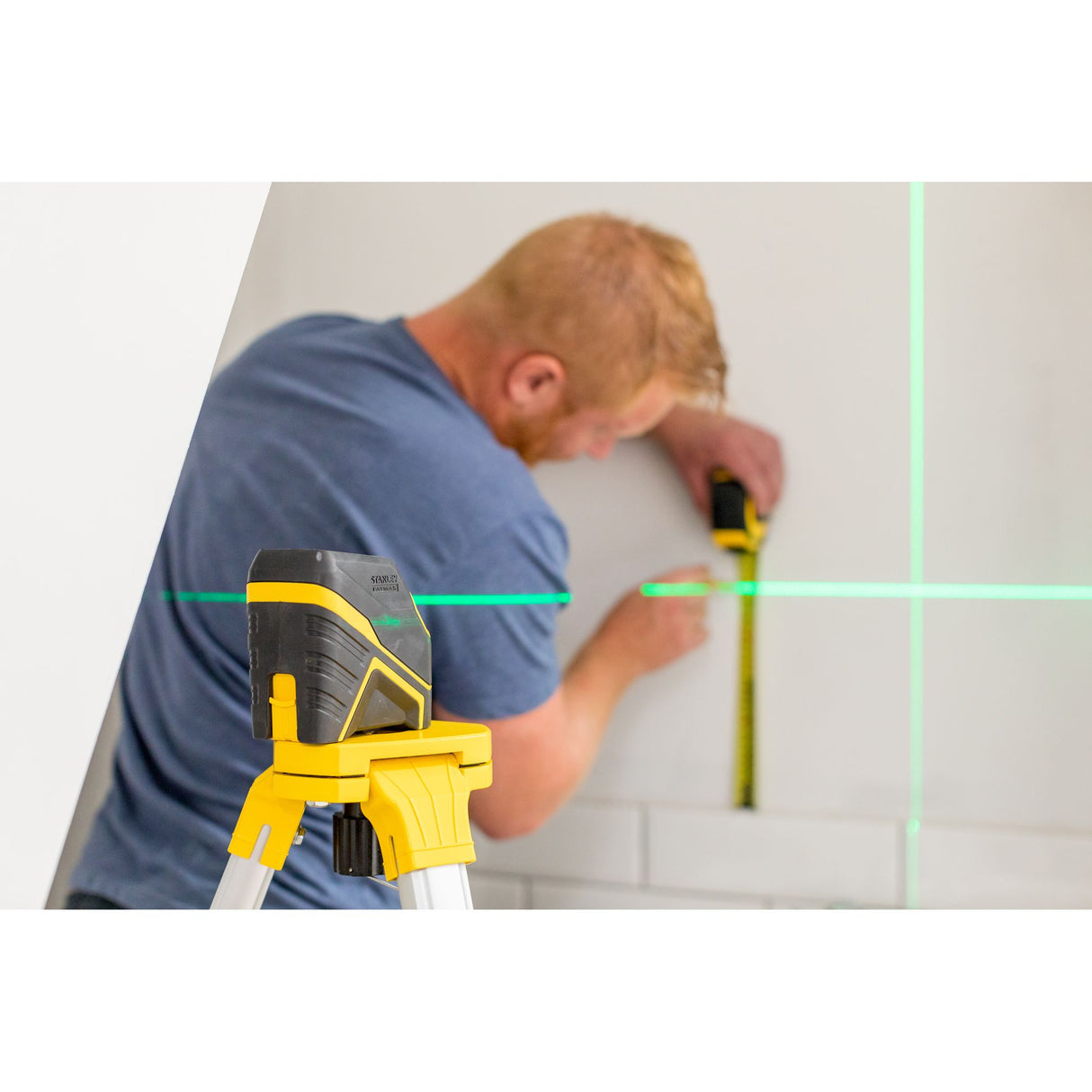 Niveau laser Stanley noir et jaune utilisé pour mesurer sur un mur, ligne verte visible