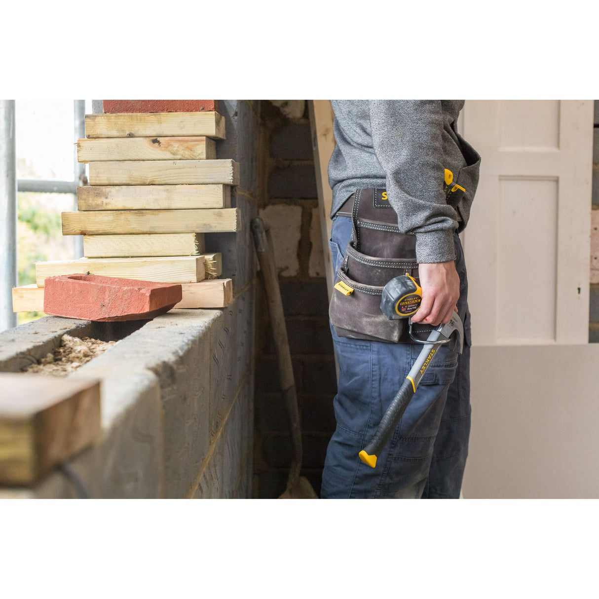 Marteau Stanley de bricolage, couleur noir et jaune, porté à la ceinture.