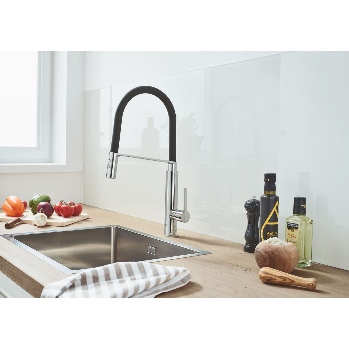 Mitigeur cuisine Grohe, couleur chrome et noir, installé sur un évier inox moderne.