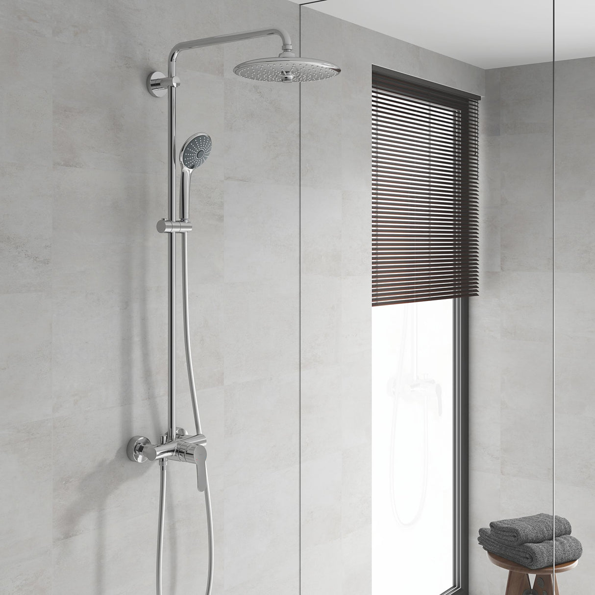 Colonne de douche Grohe, chromée, avec pommeau rond sur mur de salle de bain claire.