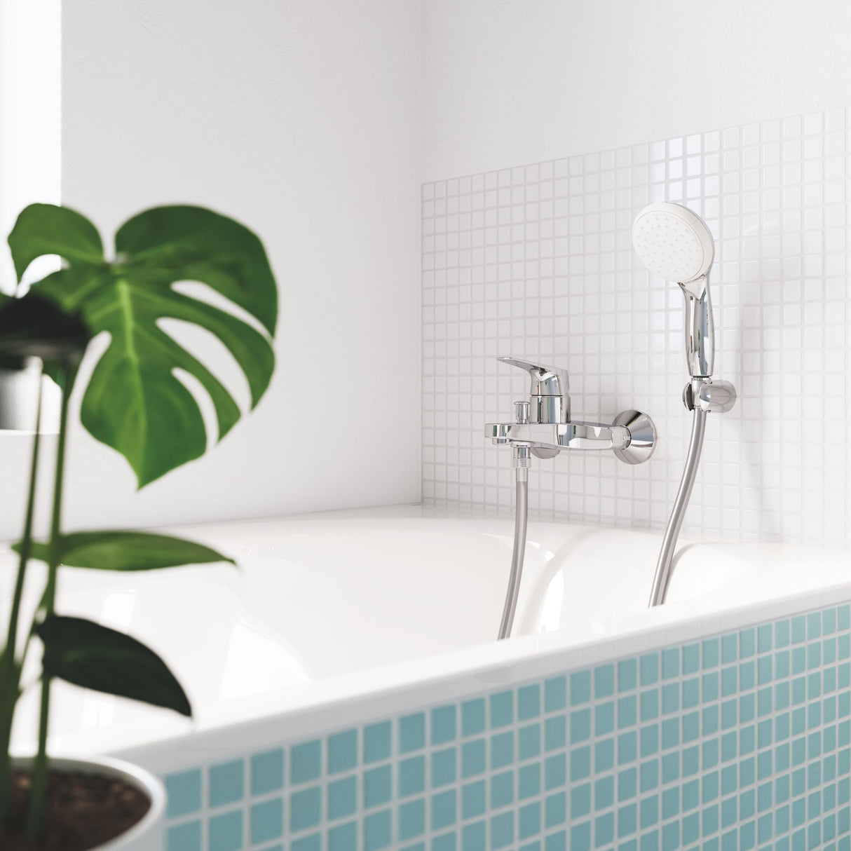 Mitigeur de baignoire chromé Grohe avec douchette, couleur argent, installé sur carrelage blanc.