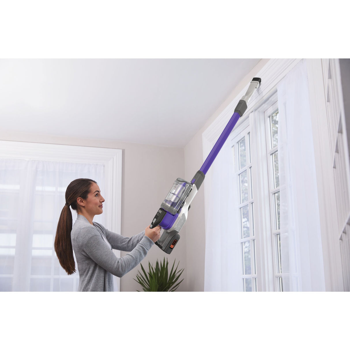 Aspirateur balai Bissell sans fil violet utilisé pour nettoyer en hauteur, dans une maison lumineuse.