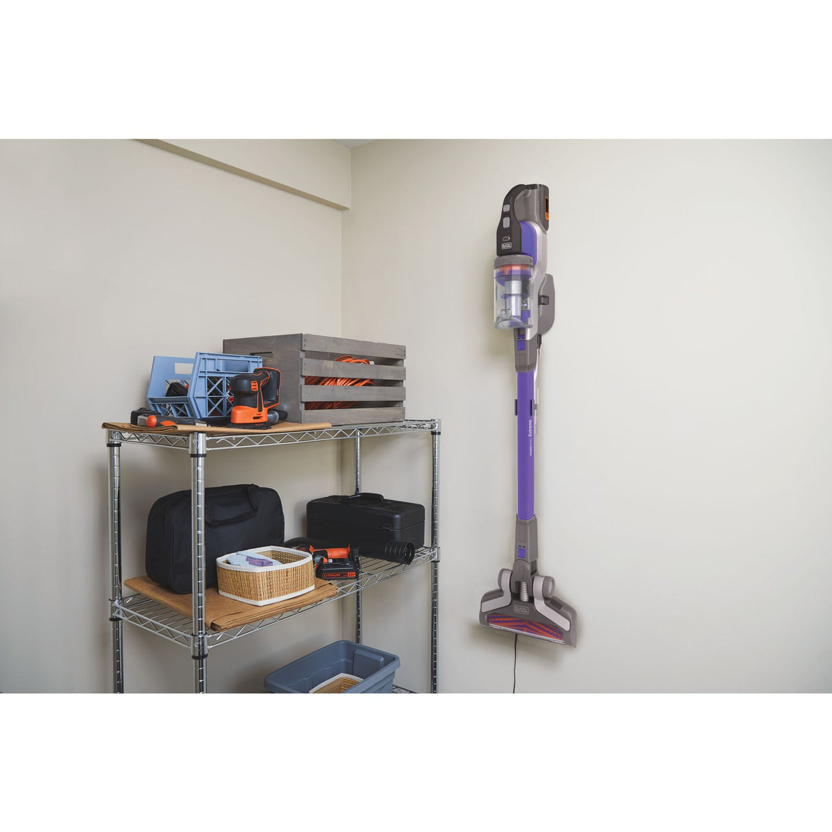 Aspirateur balai Black+Decker sans fil, violet, fixé au mur dans une buanderie.