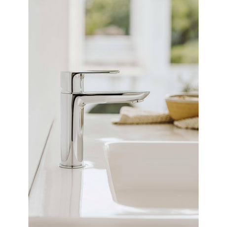 Mitigeur lavabo chromé Grohe moderne, couleur argent, installé sur un évier blanc.