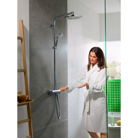 Femme utilisant une colonne de douche Grohe, finition chromée, dans une salle de bain moderne.