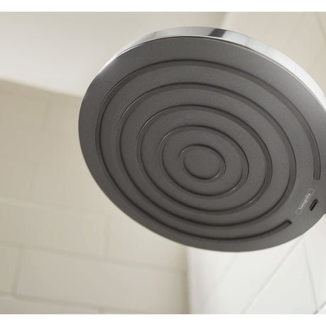 Pommeau de douche Impey, gris, de forme ronde, installé sur carrelage mural blanc.