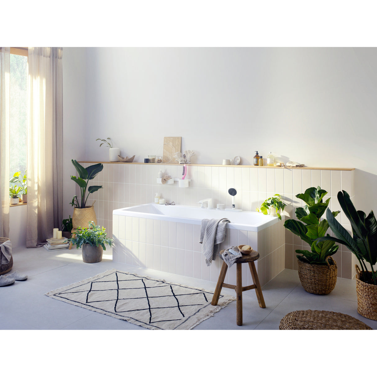 Baignoire rectangulaire blanche de la marque Hansgrohe dans une salle de bain moderne lumineuse, entourée de plantes vertes.