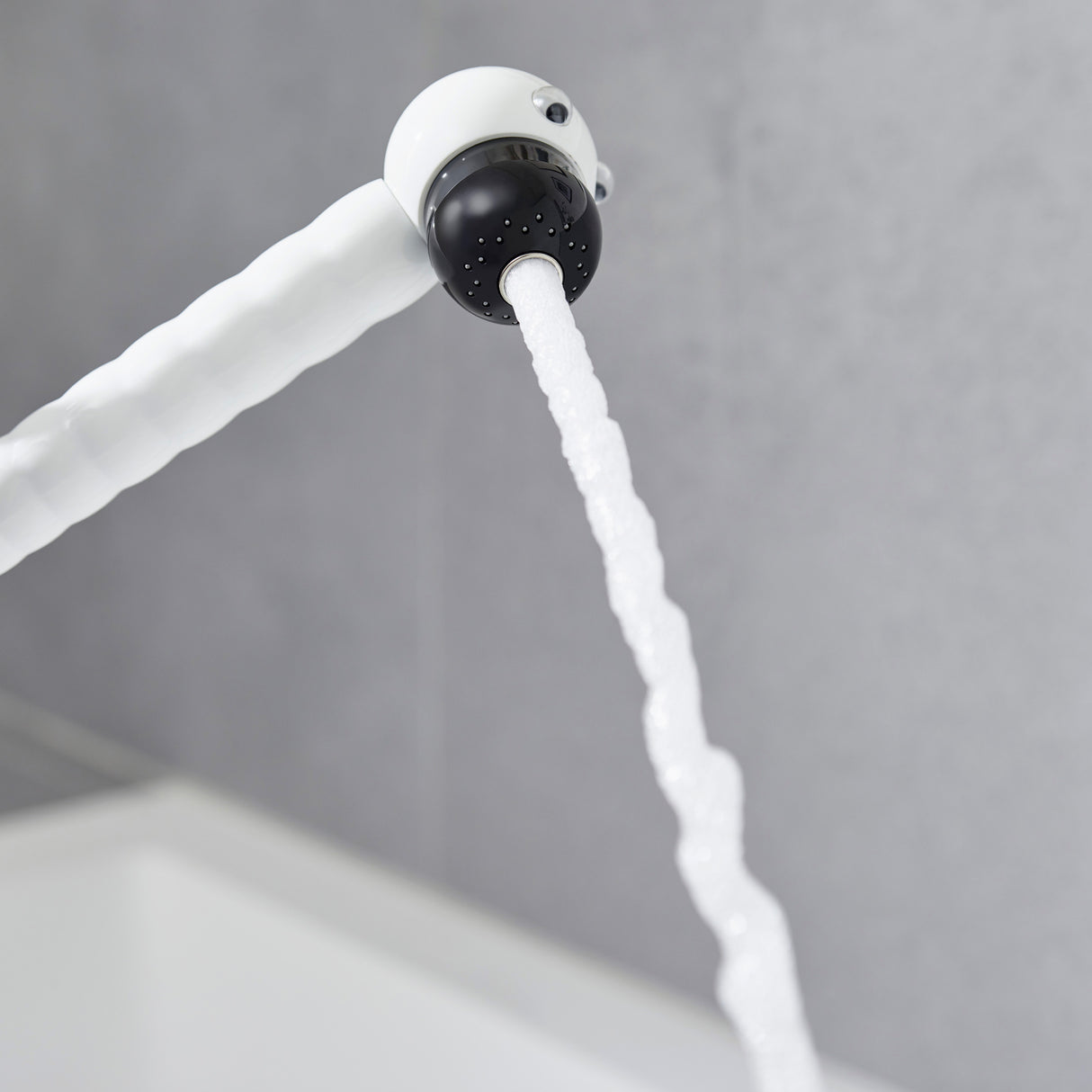 Mitigeur blanc Grohe, robinet de cuisine avec bec flexible, jet d’eau visible.